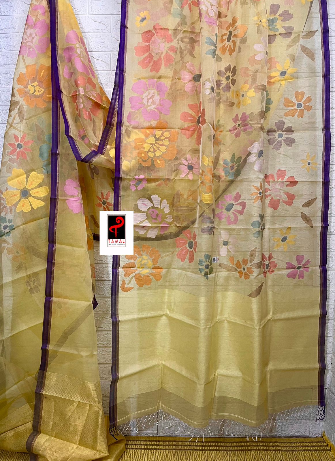 বেগুনি পাড়ের সাথে হালকা হলুদ মসলিন সিল্কে মৌসুমি ফুলের হাতে বোনা জামদানি শাড়ি